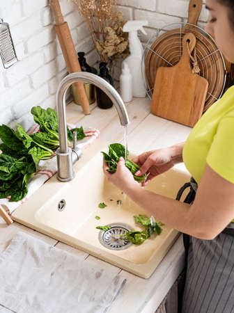 Preparing healthy foods. Healthy eating and dieting. Young smiling woman in home clothes washing...