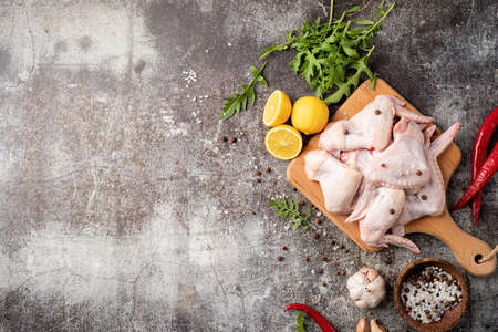 Sliced chicken wings with skin on a cutting board. Dark background with copy spaceの写真素材