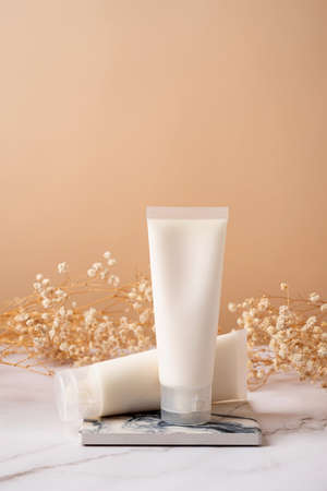 Cream tube mockup for branding presentation. Natural skincare beauty product on square marble podium. Natural earthy colors, beige backgroundの写真素材
