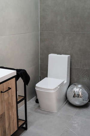 toilet and small washbasin in simple bathroom in gray floor