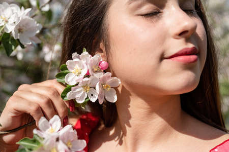 spring concept. Nature.Young caucasian woman in red dress and summer hat enjoying the flowering of an apple trees, walking in spring apple gardensの写真素材