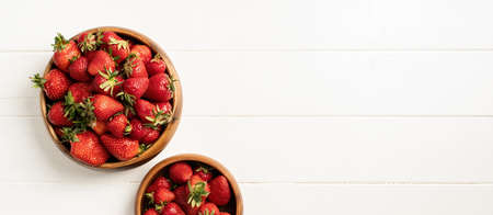 Top view bowls with fresh organic strawberries on white wooden backgroundの写真素材