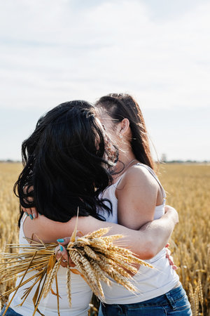 freedom, friendship concept. Two smiling female friends in white shirts in the wheat fieldの写真素材