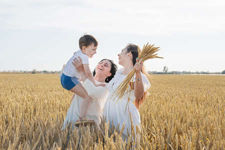 happy family of three people, mother and two children walking on wheat fieldの写真素材