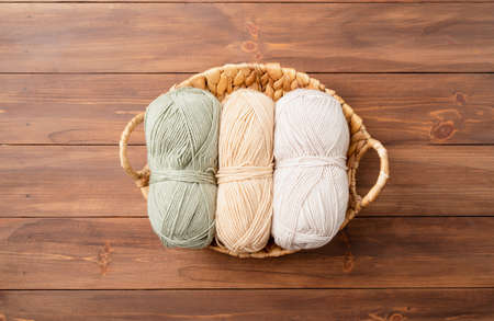 pastel colored yarn wool in a basket on wooden background