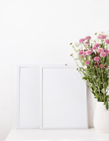 White frame mockup with chrysanthemum flowers in a vase on a white table, mockup designの写真素材