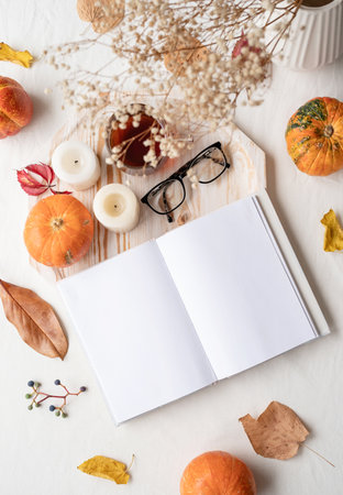 back to school. Cozy autumn. white blank book with autumn leaves, glasses and candles on white table , mockup designの写真素材