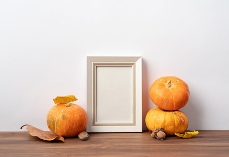 Photo frame and white pumpkins. Mockup copy space for artwork. Autumn decor interior.の写真素材