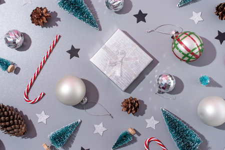 Merry Christmas and happy new year. christmas background with decorations, frame made of gifts, candy canes, balls and trees on gray background, flat layの写真素材