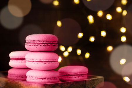 Stack of macaroons on the table, fairy lights and bokeh background, Christmas food toned with viva magentaの写真素材