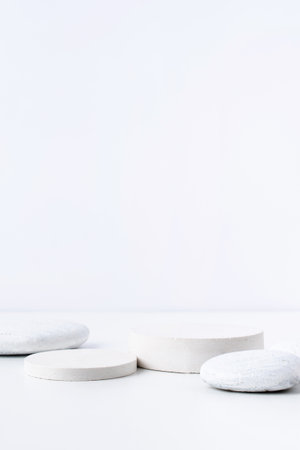 A minimalistic scene of white gypsum podium with stones on white background. Round white catwalk for the presentation of products and cosmeticsの写真素材