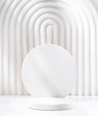 A minimalistic scene of a gypsum podium with stones on white background. Round white catwalk for the presentation of products and cosmetics. Showcase with a stage for products, mockup design, seasonalの写真素材