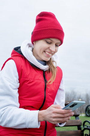 Woman wearing sport clothes sitting in the park using smartphoneの写真素材