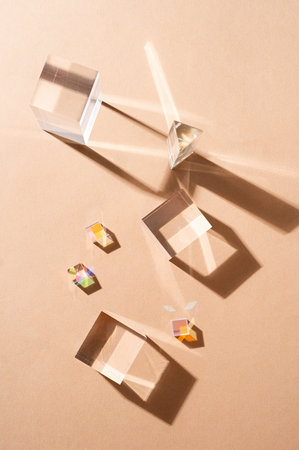 Glass prisms reflect light making beautiful shadows on beige background, glass podiums for beauty...