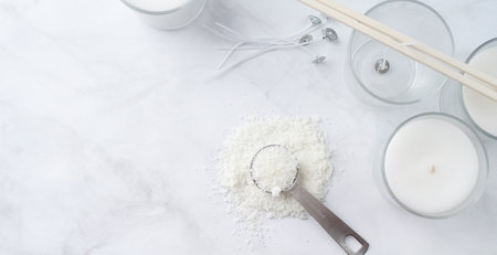 ingredients for candle making , soy wax flakes, candles, wicks on light marble background, blank label for design mockupの写真素材