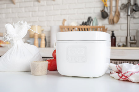 kitchen appliances and devices. Electric smart rice cooker on wooden counter-top in the kitchen with basmati riceの写真素材