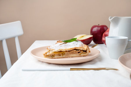 autumn food. Homemade piece of apple pie with fresh red apples on white dining table, beige wallの写真素材