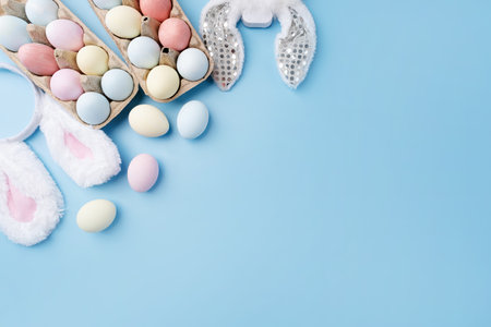 Spring holidays, Happy Easter. Pastel colored Easter eggs and bunny ears on blue background with...