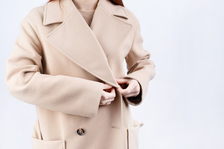 closeup woman in beige coat choosing outfit dressing on white background. Selection of a wardrobe, stylist, shopping.の写真素材