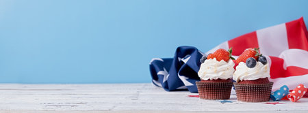 Fourth of july celebration.Sweet cupcakes with blueberries and strawberries , flag backgroundの写真素材