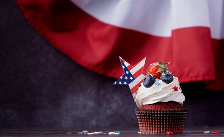 Fourth of july celebration. Sweet cupcakes with blueberries and strawberry over USA flag backgroundの写真素材