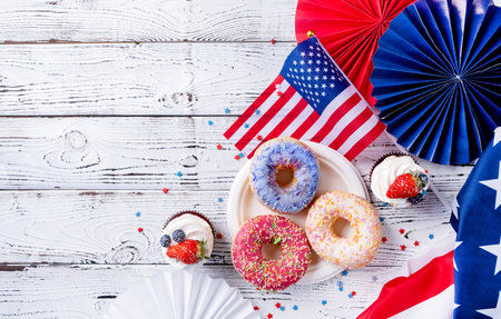 Fourth of july celebration. Sweet cupcakes and donuts with usa flag on wooden backgroundの写真素材