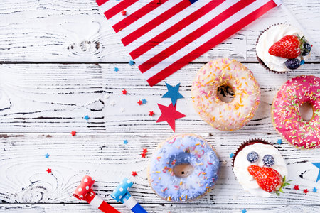 Fourth of july celebration. Sweet cupcakes and donuts with usa flag on wooden backgroundの写真素材