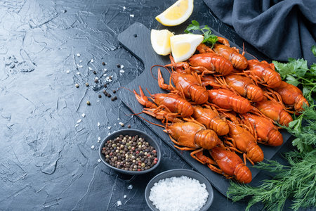 cooked crawfish on cutting board with lemons and spices on dark backgroundの写真素材