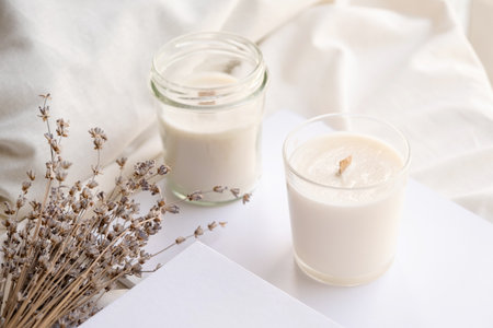 Soy wax aroma candles in jar on bed with lavender flowers. Candle mockup design. Mockup soy wax candle in natural style.の写真素材