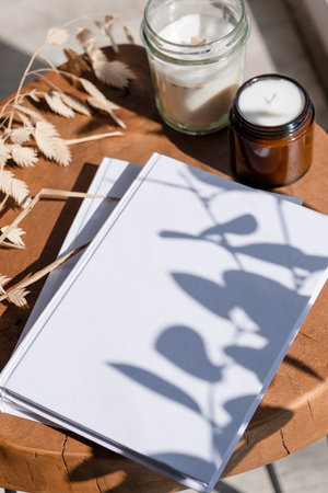 Magazine and book mockup design. Blank magazine on modern wooden table with candles, shadow overlay....