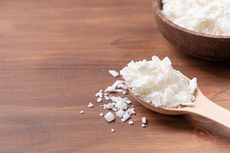 Soy wax for home-made natural white soy wax candles. Closeup of soy wax in wooden spoon on wooden...