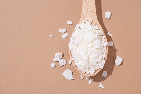 Soy wax for home-made natural white soy wax candles. Closeup of soy wax in wooden spoon on brown background, copy spaceの写真素材
