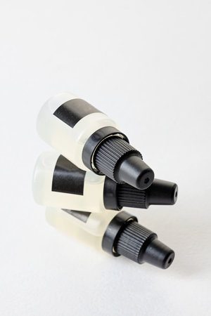 Set of plastic dropper bottles with liquid with black blank stickers. Mockup on white background...