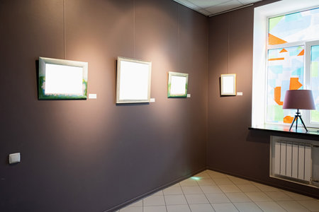 Blank picture frames on brown wall with glowing lamp in the gallery, mock upの写真素材