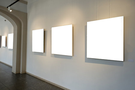 Blank picture frames on gray wall with glowing lamp in the gallery , mock up