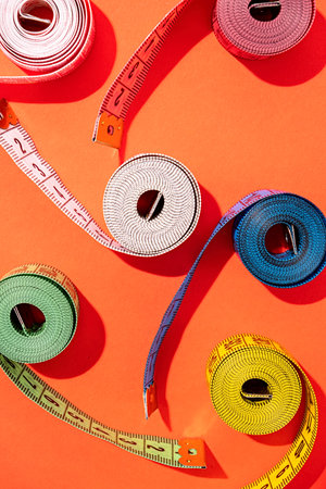 Dieting concept. colorful measuring tapes top view on bright red background, flat lay, patternの写真素材