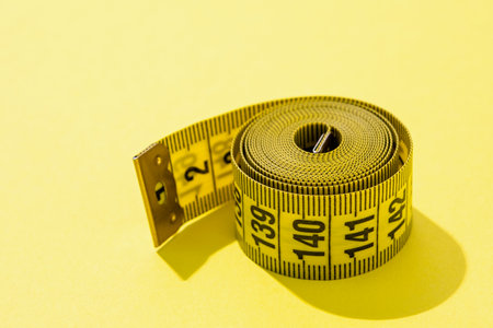 Dieting concept. colorful measuring tapes top view on bright yellow backgroundの写真素材