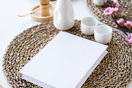 Book mockup design. Blank white book on dining table in Asian style with tableware and napkins