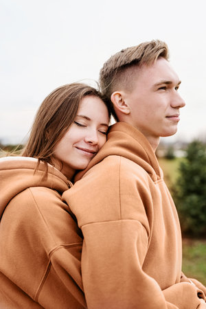 Color of the year 2024: Peach Fuzz. Valentines Day. young loving couple wearing trendy colored peach fuzz sweatshirts hugging outdoorsの写真素材