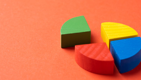 Colorful wooden pie chart pieces on bright red background with copy spaceの写真素材