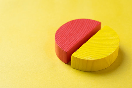 Colorful wooden pie chart pieces on bright yellow background with copy spaceの写真素材