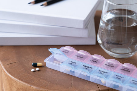 Closeup of medical pill box with doses of tablets for daily take a medicine and glass of waterの写真素材