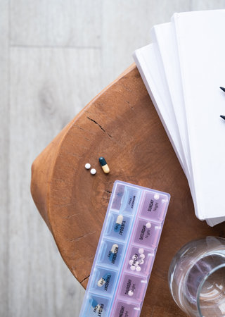 Closeup of medical pill box with doses of tablets for daily take a medicine and glass of water