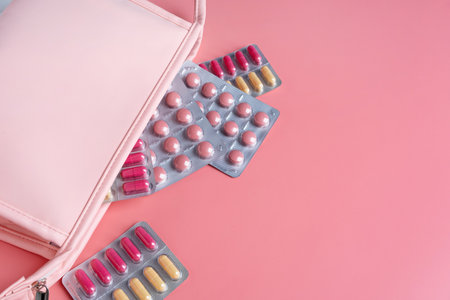 Flat lay composition with pink female cosmetic bag blisters on color background. womens healthの写真素材