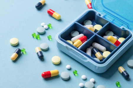 composition with pill box and pills on blue color backgroundの写真素材