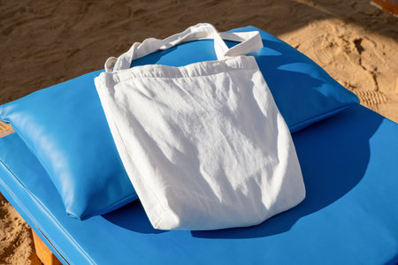 Mockup shopper handbag on blue lounger, beach sand background. Top view copy space shopping eco...