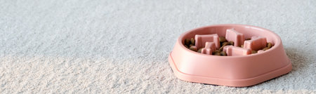 orange dog bowl filled with dog food, with a maze design in the shape of dog bones to slow down fast eatersの写真素材