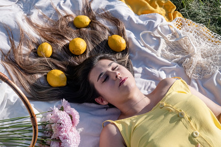 Spring concept. Nature. Young caucasian woman wearing yellow dress, having a picnic, lemons in hair