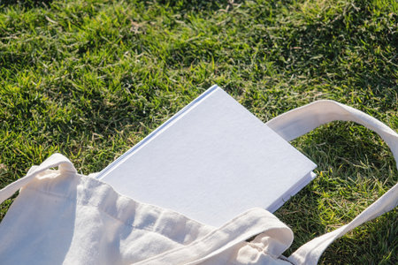 Mockup shopper handbag and book, green grass background. Top view copy space shopping eco reusable bag.の写真素材