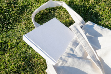 Mockup shopper handbag and book, green grass background. Top view copy space shopping eco reusable bag.の写真素材